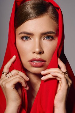 Şık bir kadın zarif bir şekilde poz verir, canlı kırmızı bir başörtüsüne güvenir..