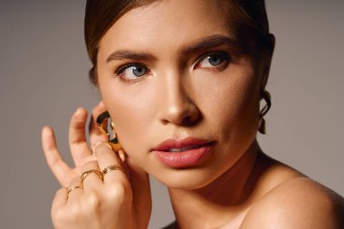 Zarif bir kadın, özgüven ve zarafet saçarak, gözüne küpe takarak nazikçe ayarlar..