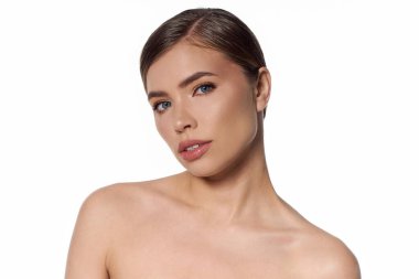 Kendine güvenen genç bir kadın, kusursuz bir cilt ve şık bir stil sergileyen izleyiciye bakıyor..