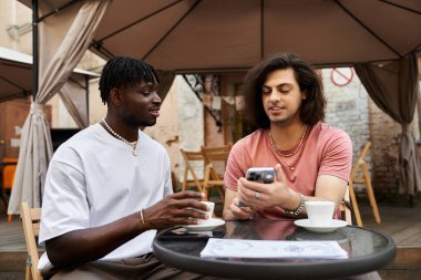 İki yakışıklı adam bir kafede birlikte telefona bakarken keyifli bir anı paylaşıyor..