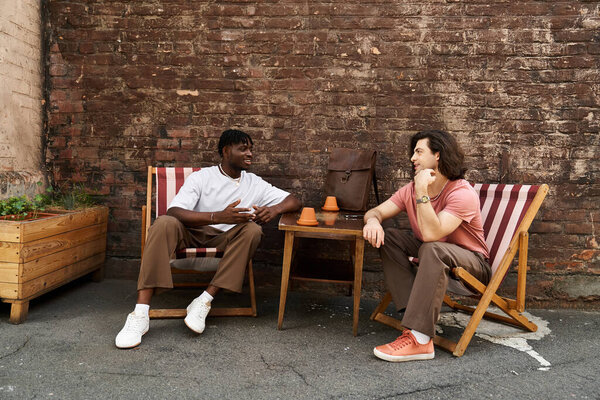 Два красивых мужчины делятся смехом и беседой за чашечкой кофе, наслаждаясь своим особым временем вместе.