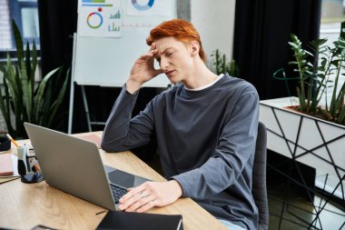 Dedicated young professional with red hair solving complex work challenges at desk. clipart