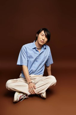 Yakışıklı genç bir adam, sıcak bir stüdyo arkaplanı ile çevrili şık bir kıyafetle güven içinde poz verir..