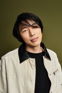 Şık genç adam kendine güvenen bir şekilde stüdyoda poz veriyor, şık kıyafetlerini ve karizmasını sergiliyor..