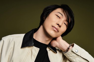 Genç Asyalı bir adam stüdyoda poz verirken eşsiz moda anlayışını sergiliyor..