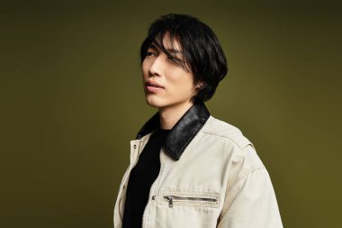 Şık bir genç adam dikkat çekici bir arka planla stüdyoda güven içinde poz veriyor..