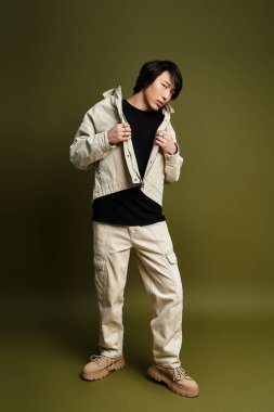 Genç Asyalı bir adam sağlam bir arkaplana karşı şık bir elbiseyle poz veriyor..