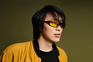 Genç Asyalı bir adam, kendine güveni ve cazibesi ile canlı bir stüdyoda moda anlayışını sergiliyor..