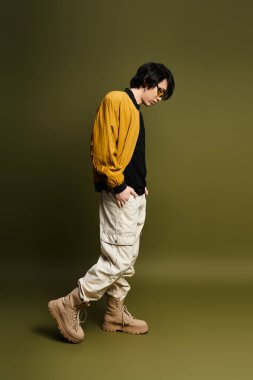 Genç Asyalı bir adam moda anlayışını gösteriyor. Stüdyoda modaya uygun kıyafetler giyiyor..