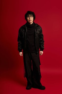 Siyah elbiseli genç Asyalı kırmızı bir stüdyoda poz veriyor..