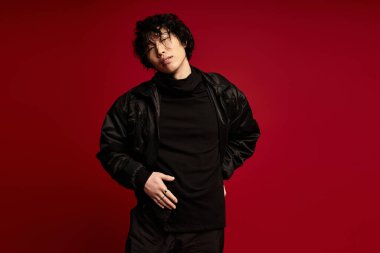 Siyahlı genç Asyalı adam, kırmızıya karşı düşünceli bir şekilde poz verdi..