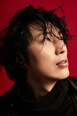 Kırmızı stüdyoda poz veren şık Asyalı genç adam..