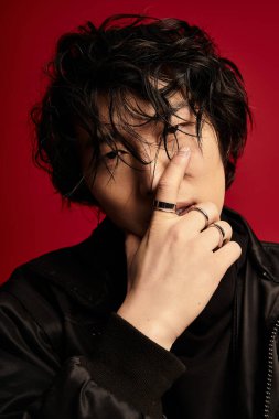 Stüdyoda kırmızı arka planda poz veren şık Asyalı genç adam..