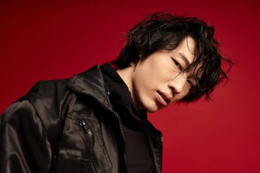 Siyah ceketli Asyalı adam kırmızıya bakıyor..