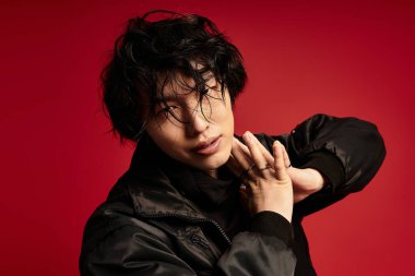 Genç Asyalı bir adam stüdyo ortamında şık bir poz veriyor. Kendine güveni ve modern yeteneği var..