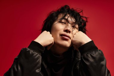 Genç Asyalı adam elleri ve gözleri kapalı dinleniyor. Kırmızı arkaplan.