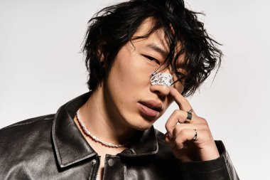 Deri ceketli, burnu alçılı genç Asyalı stüdyoda poz veriyor..