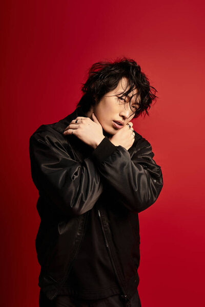 A young, fashionable asian man poses in a red stylish studio.