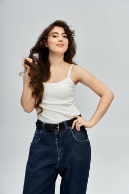 Dalgalı saçlı genç bir kadın, eşsiz tarzını ve neşesini sergileyerek neşeli bir poz verir..