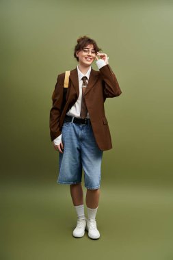 Şık genç bir kadın, modaya uygun yeteneğini sergileyerek, eşsiz bir kıyafet içinde neşeli bir şekilde poz verir..