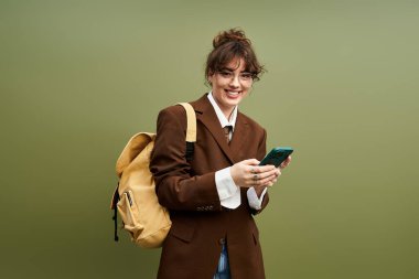 Şık bir spor ceketle telefonunu kontrol ederken parlak bir gülümseme yüzünü aydınlatıyor..