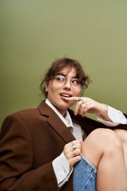Çekici genç bir kadın, canlı bir arkaplana karşı modaya uygun bir kıyafete güveniyor..