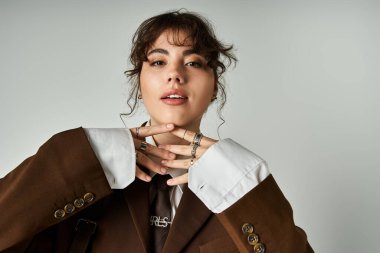 Şık genç kadın zarafet ve zarafetle poz veriyor, şık kıyafetlerini ve aksesuarlarını vurguluyor..