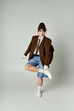 Minimalist bir stüdyoda şık bir kadın şık kıyafetini şort ve spor ceketiyle gösterir..