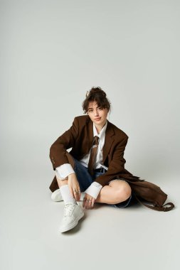 Kendine güvenen genç bir kadın modaya uygun bir kıyafetle minimalist bir mekanda oturuyor..