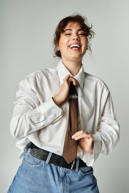 Parlak, neşeli, şık giyinmiş genç bir kadın kravatını düzeltiyor ve neşeli bir anın tadını çıkarıyor..