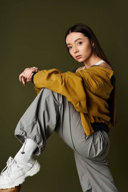 Kendine güvenen genç bir kadın, kendine özgü moda tarzını canlı bir arkaplanda sergiliyor..