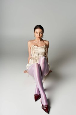 Genç bir kadın zarif kıyafetiyle gösteriş yapıyor. Minimalist bir ortamda, kendinden emin..