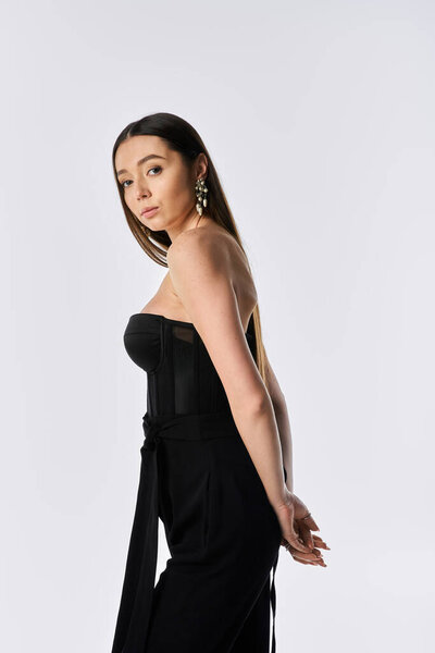 Модная женщина элегантно стоит, демонстрируя свой современный стиль и уверенность.