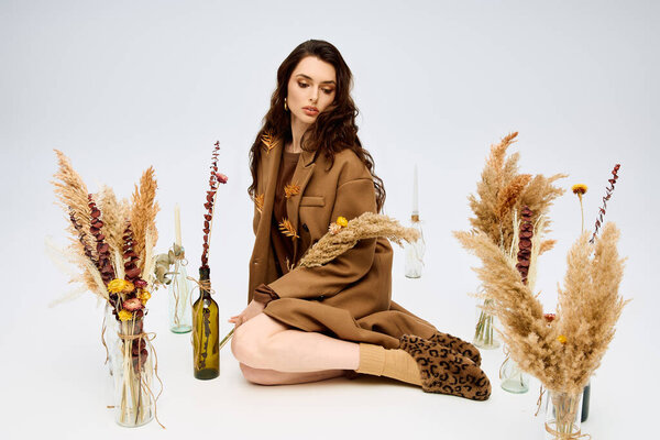 Молодая женщина с длинными каштановыми волосами радостно позирует среди весенних цветов.