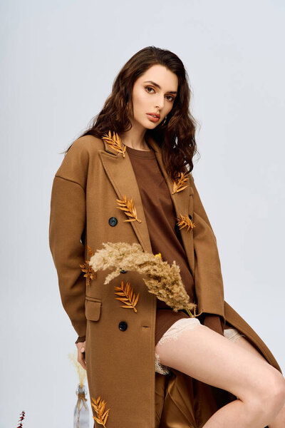 грациозная молодая женщина с длинными каштановыми волосами стоит среди весенних цветов.