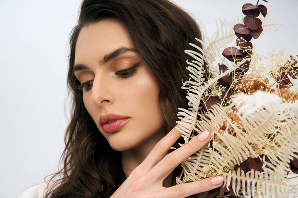 Весной молодая женщина с каштановыми волосами нежно взаимодействует с красочными цветами..