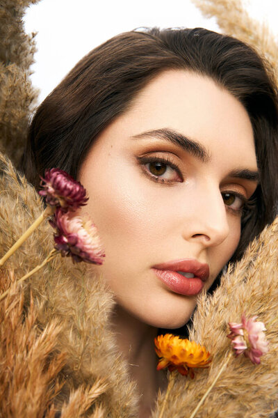 Молодая женщина с каштановыми волосами наслаждается красотой ярких цветов в весенне-вдохновленной обстановке.