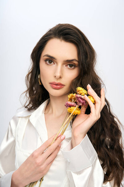 Among vibrant flowers, a beautiful young woman with brown hair radiates spring elegance.