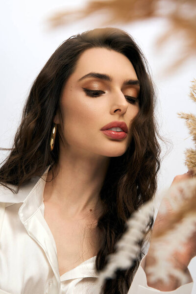 Молодая женщина с каштановыми волосами восхищается цветущими цветами в очаровательной весенней атмосфере.