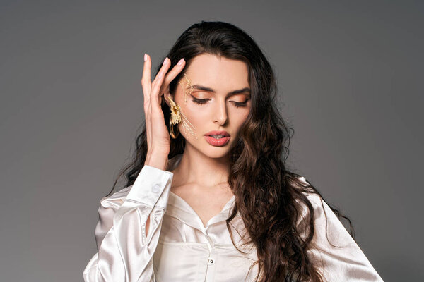 Красивая девушка с каштановыми волосами изящно позирует среди цветущих цветов весной.