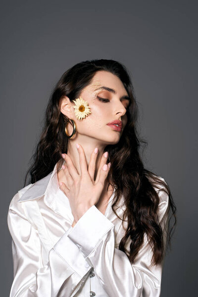 Красивая молодая женщина с каштановыми волосами изящно позирует среди цветов весной.