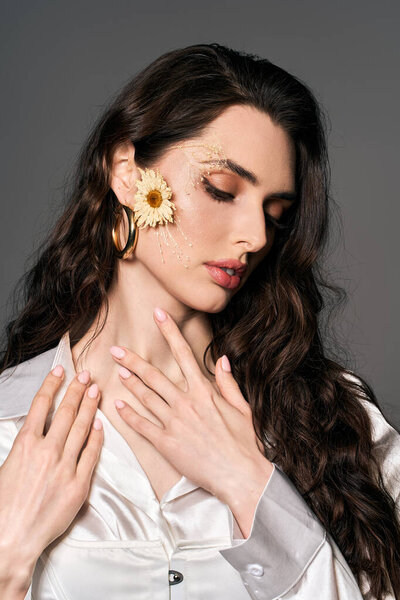 Красивая молодая женщина с каштановыми волосами, украшенными цветами изящно позирует, источая элегантность.