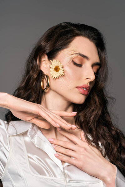 Красивая молодая женщина с каштановыми волосами изящно позирует посреди ярких цветов, олицетворяя собой весну.