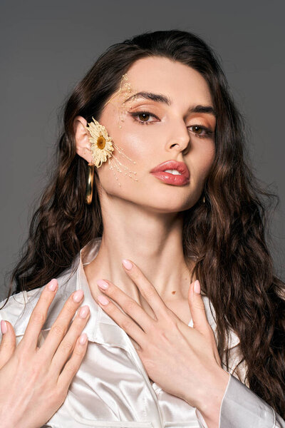 Молодая женщина с каштановыми волосами позирует среди ярких цветов, излучающих весенний дух.