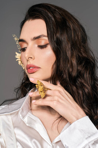 Красивая молодая женщина с каштановыми волосами нежно держит цветы, наслаждаясь весенним светом..