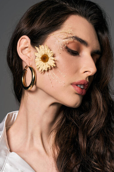 Красивая молодая женщина с каштановыми волосами сияет, как она изящно позирует среди ярких весенних цветов.