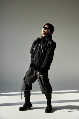 Şık, genç Asyalı bir adam kendinden emin duruyor, kafası minimalist bir ortamda eğik..