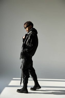 Modayı takip eden siyah giysili yakışıklı genç adam, modern tarzın özünü yakalıyor..