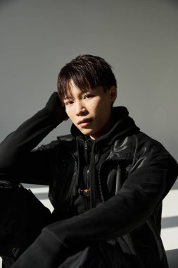Moda kıyafetli yakışıklı Asyalı adam modern bir ortamda derin düşüncelere daldı.