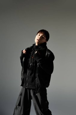 Kendine güveni olan genç adam şık siyah giysiler içinde şık bir arka plana karizma yayıyor..